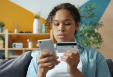 Woman holding credit card and phone for online shopping.