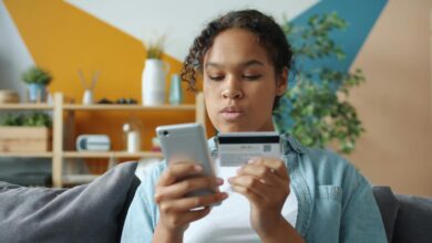 Woman holding credit card and phone for online shopping.