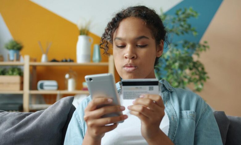 Woman holding credit card and phone for online shopping.