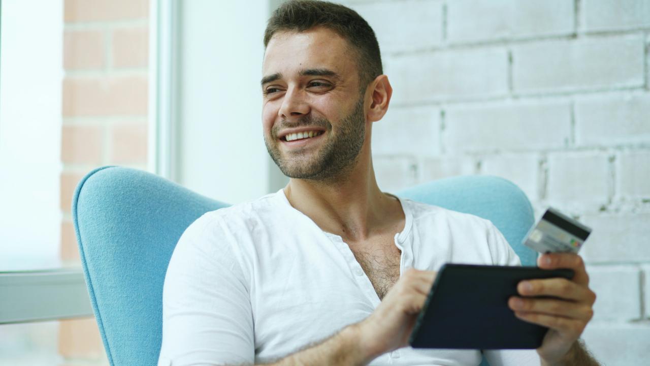 Man smiling while using tablet and credit card
